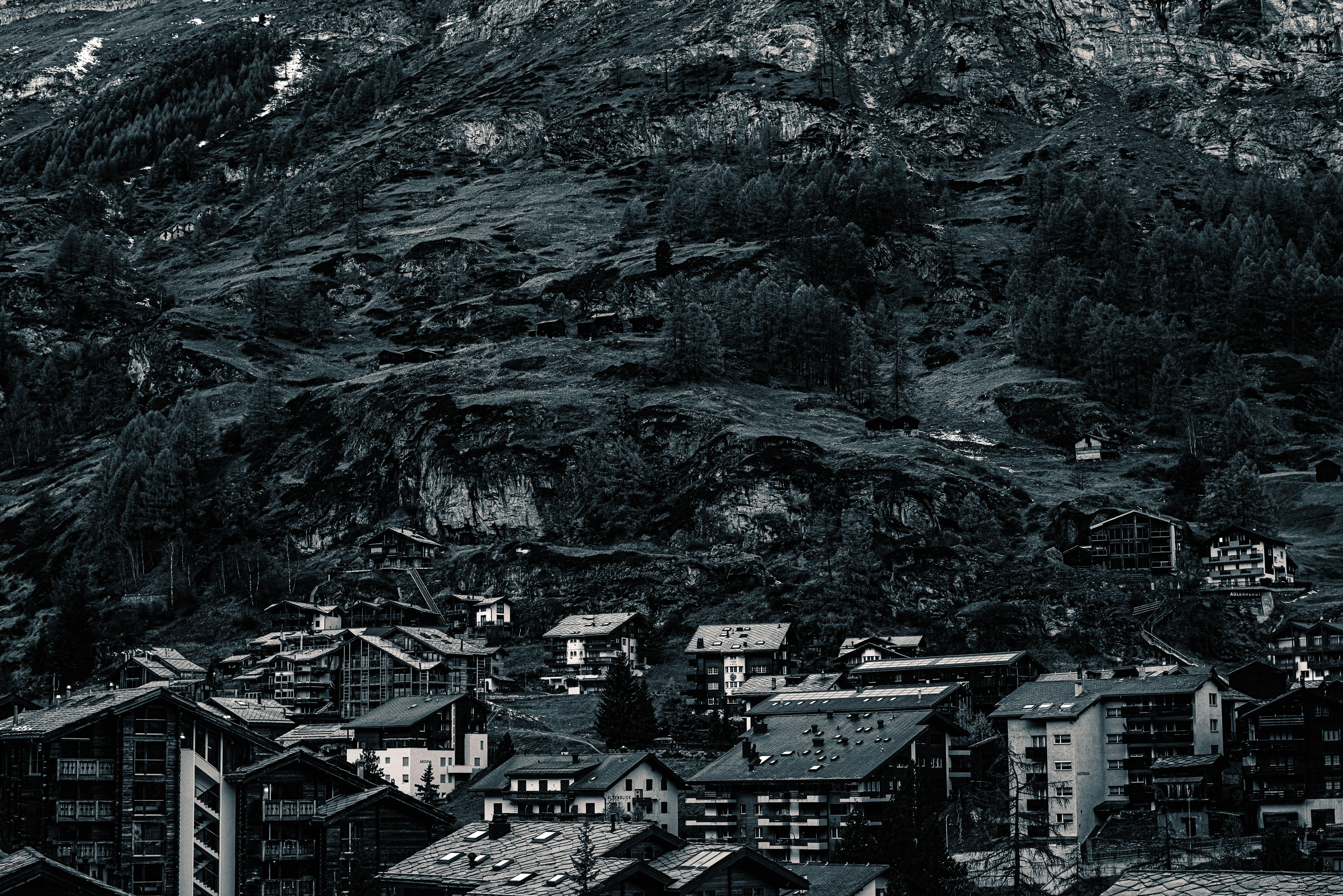 a black and white photo of a city below a mountain